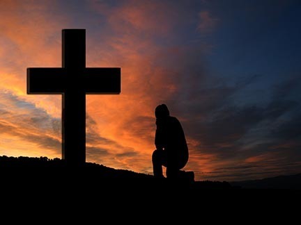 Man kneeling in front of cross